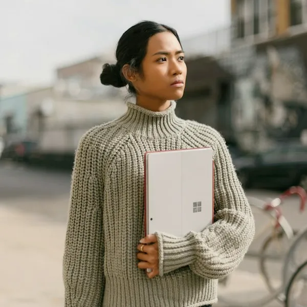 Person in a knitted jumper holding a notebook outdoors